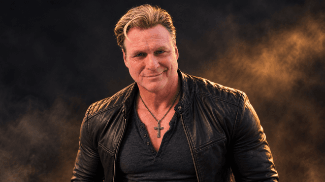 Man in a leather jacket poses confidently with a smoky background